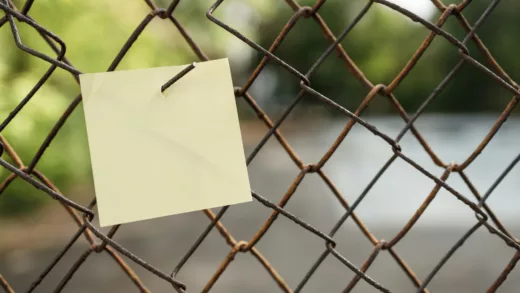 yellow sticky note on gray metal fence